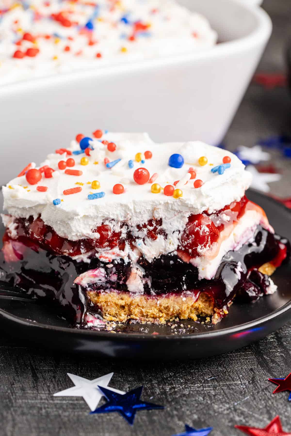 Red White and Blue Dessert Lasagna on a plate up close with a piece missing