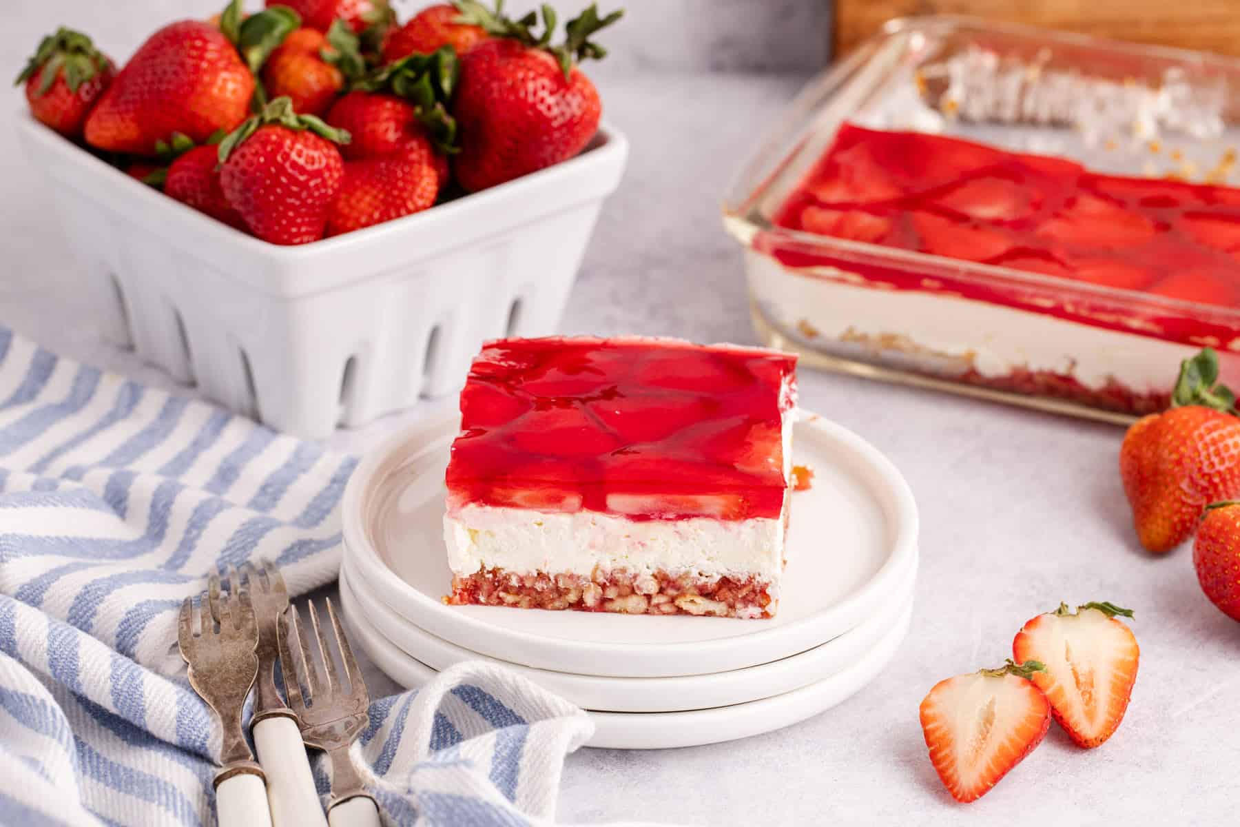 Strawberry Pretzel Salad on a plate with strawberries in the back