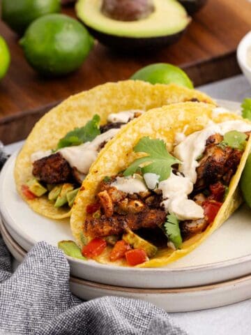 Blackened Cod Tacos on a plate with sauce and cilantro