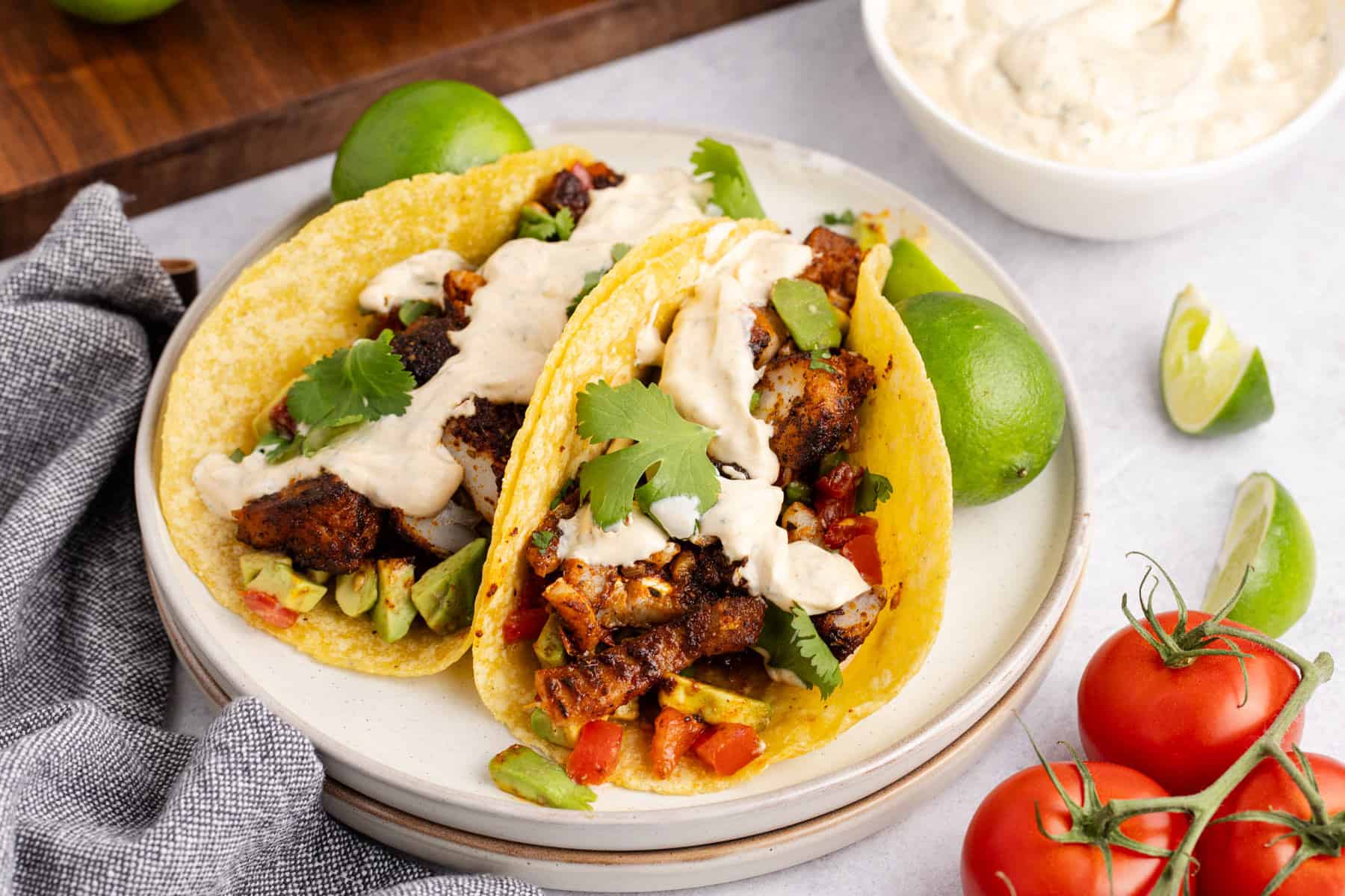 Blackened Cod Tacos on a plate with sauce and cilantro