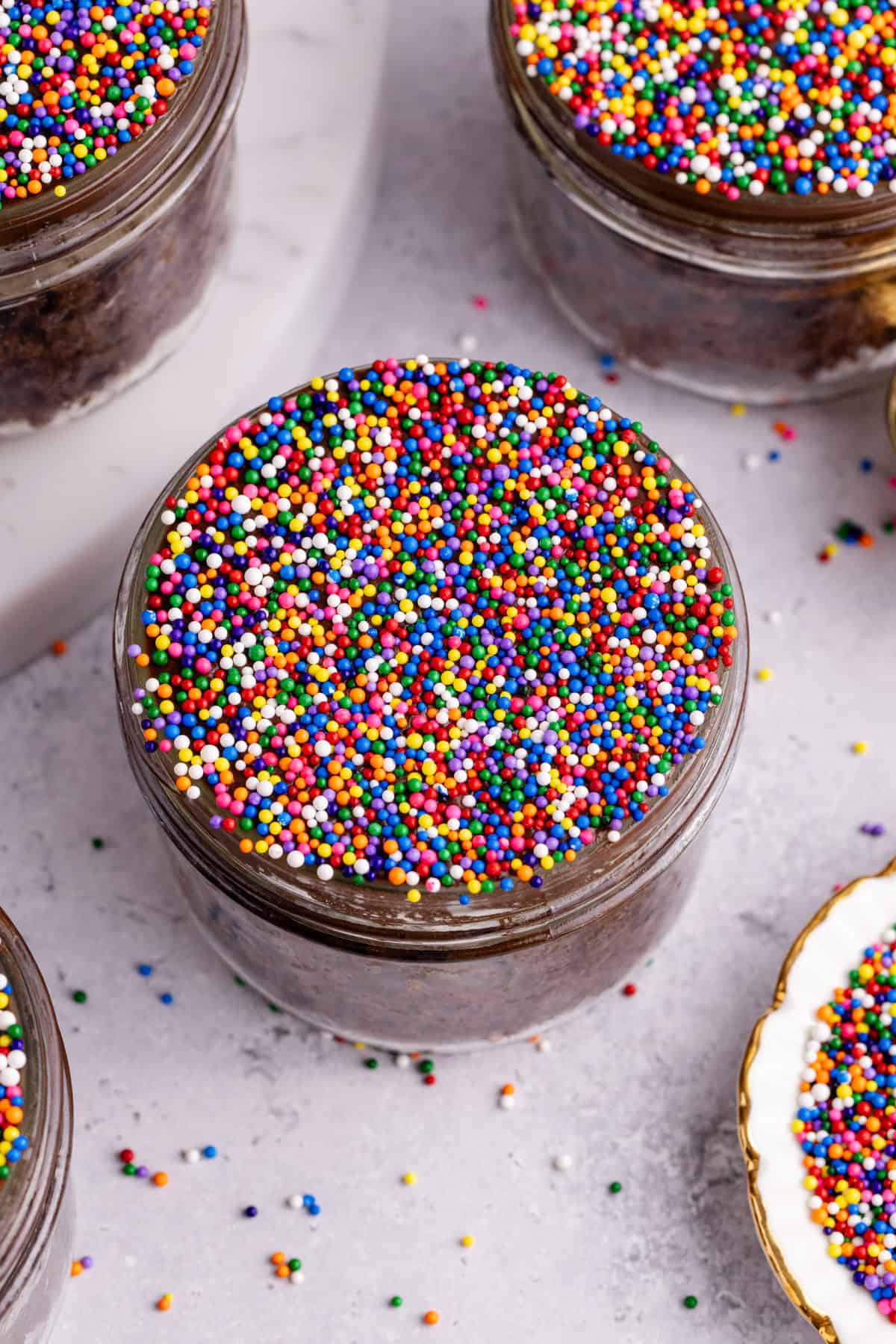 Chocolate Viral Dot Cakes in jars with rainbow sprinkles all around