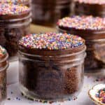 Chocolate Viral Dot Cakes in jars on a counter with sprinkles all around