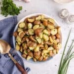 lemon herb red potato salad in a large serving bowl garnished with fresh herbs