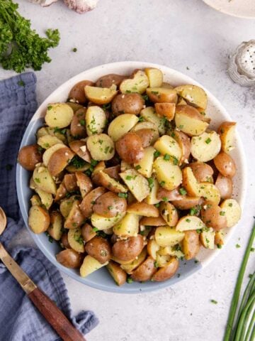 lemon herb red potato salad in a large serving bowl garnished with fresh herbs