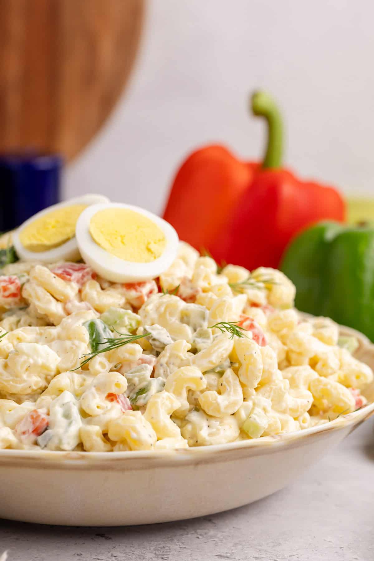 Macaroni Salad in a serving dish with fresh peppers in the background