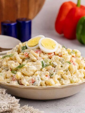 Macaroni Salad in a serving dish with fresh dill and hardboiled eggs on top