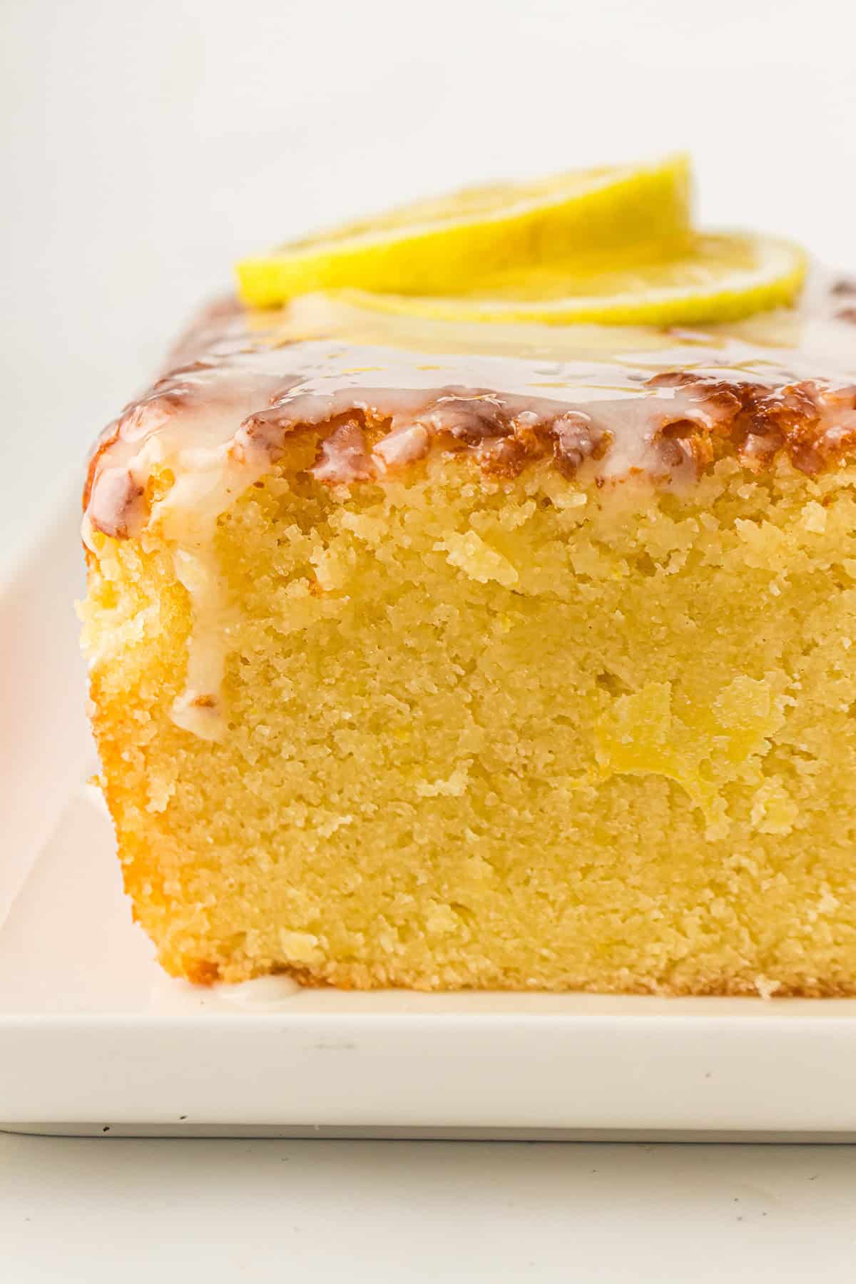 Old Fashioned Lemon Pound Cake sliced to show the moist inside with lemon slices on top