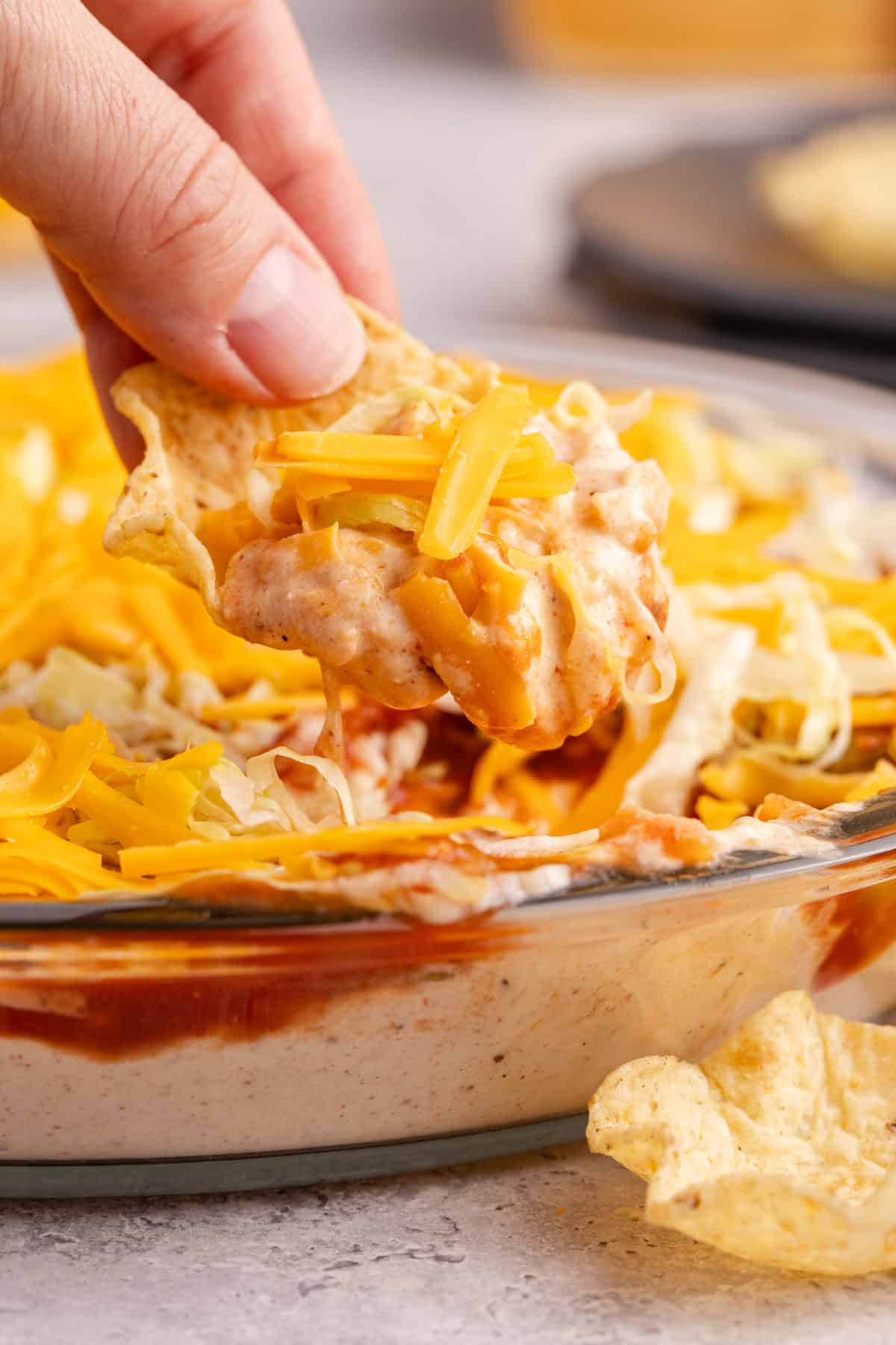 Taco Dip with Cream Cheese being scooped up close on a corn chip