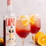 two wine glasses with aperol spritz mocktail garnished with orange slice