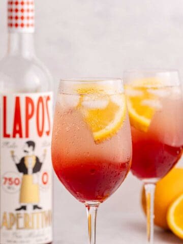 two wine glasses with aperol spritz mocktail garnished with orange slice