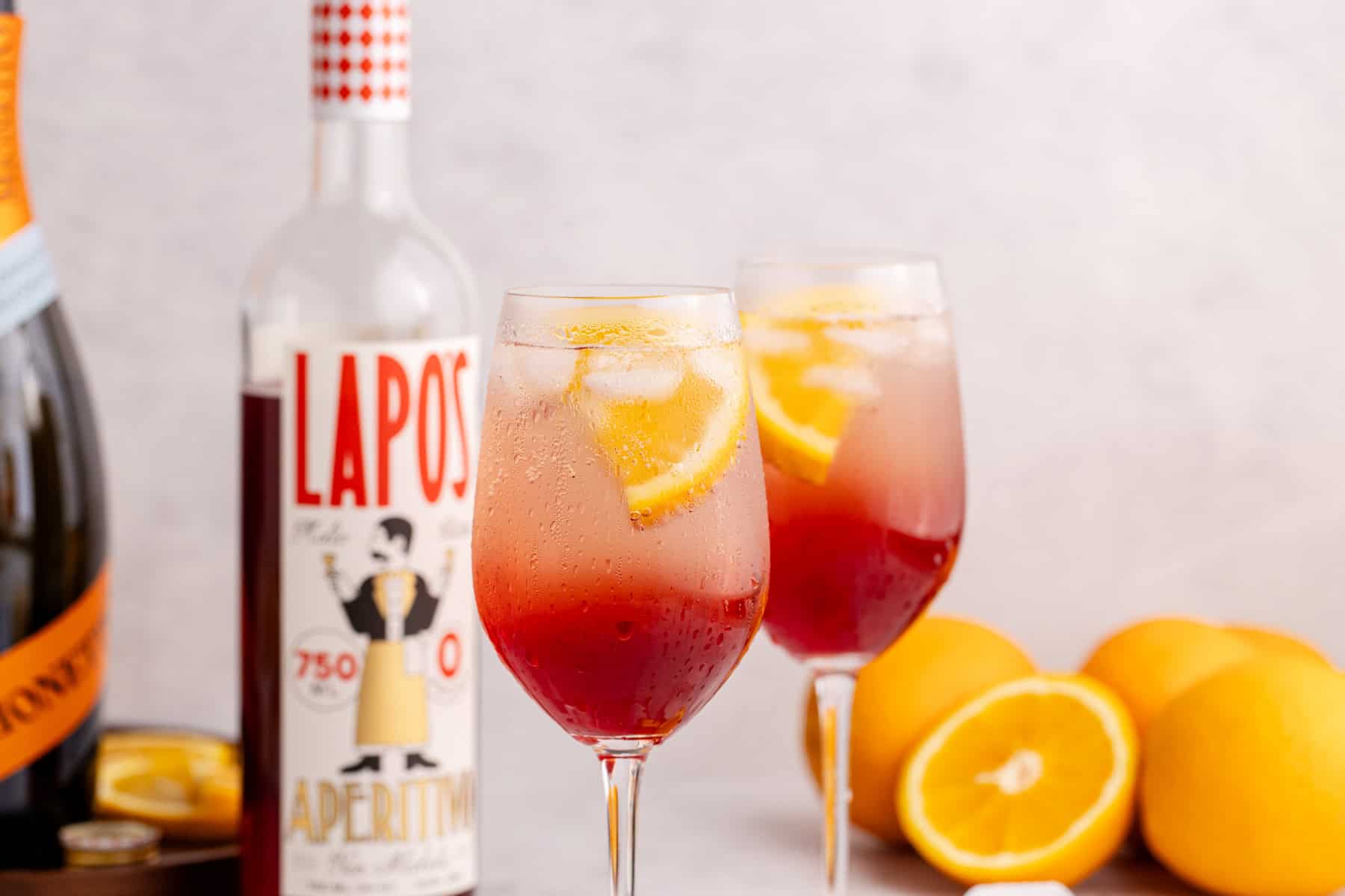 two wine glasses with aperol spritz mocktail garnished with orange slice