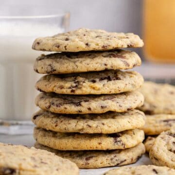 Chocolate Chip Vanilla Pudding Cookies stacked with a glass of milk in the back