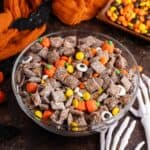 Halloween Puppy Chow in a bowl with skeleton hands reaching for it