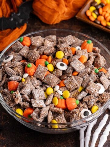 Halloween Puppy Chow in a bowl with skeleton hands reaching for it