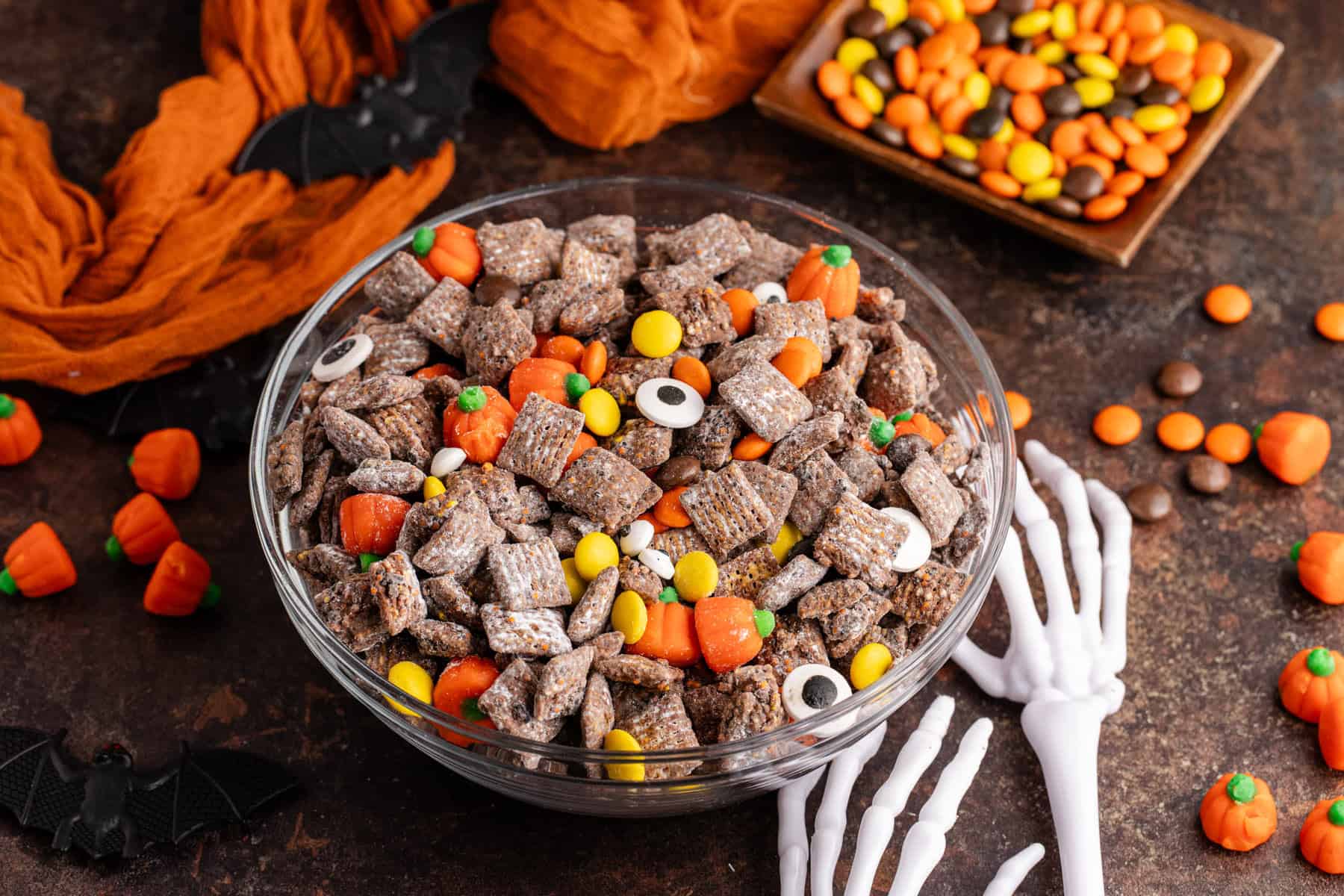 Halloween Puppy Chow in a bowl with skeleton hands reaching for it