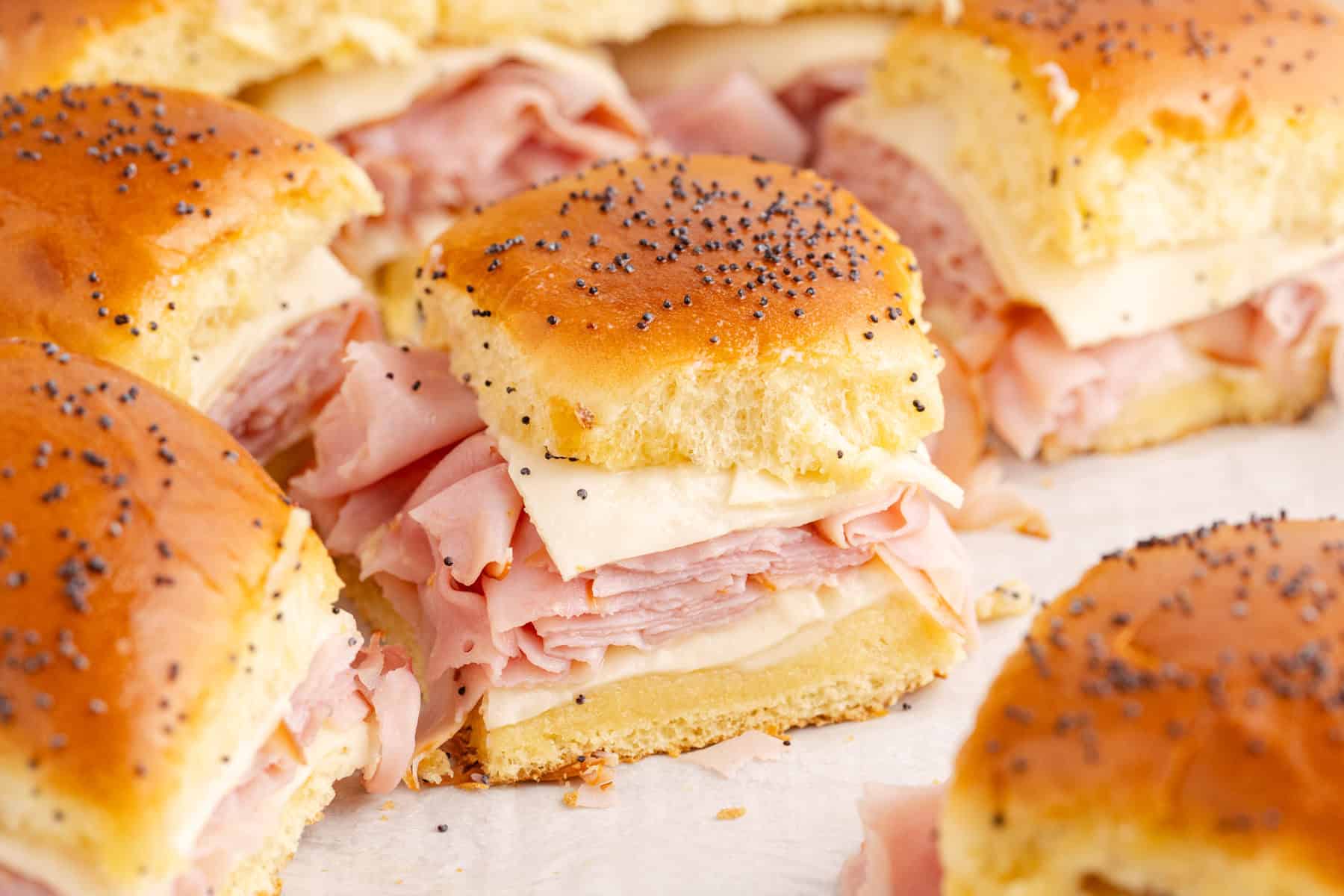 ham and cheese sliders on hawaiian roll buns topped with poppyseeds