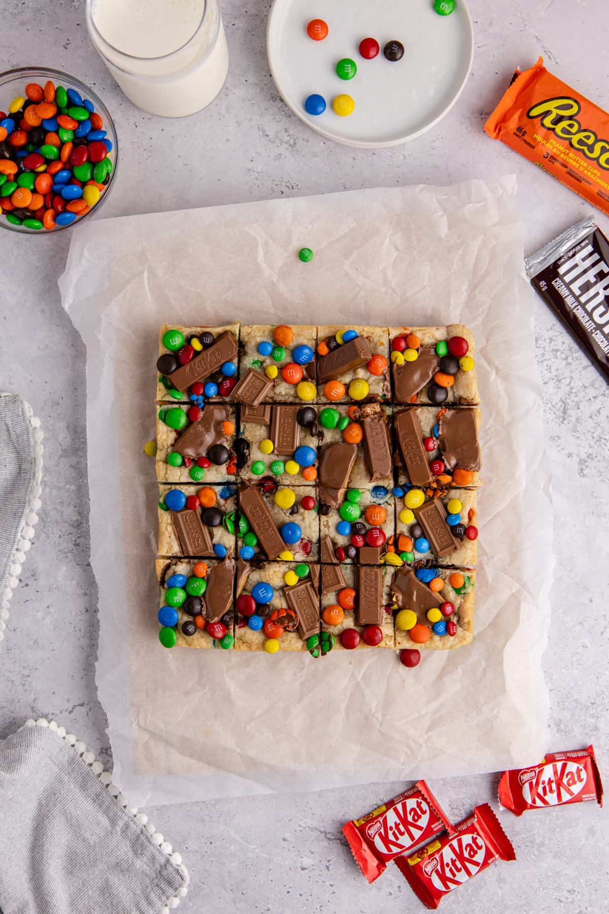 Leftover Candy Cookie Bar from above after cooling on parchment paper with candies all around