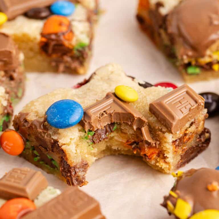 Leftover Candy Cookie Bars on parchment with a bite taken