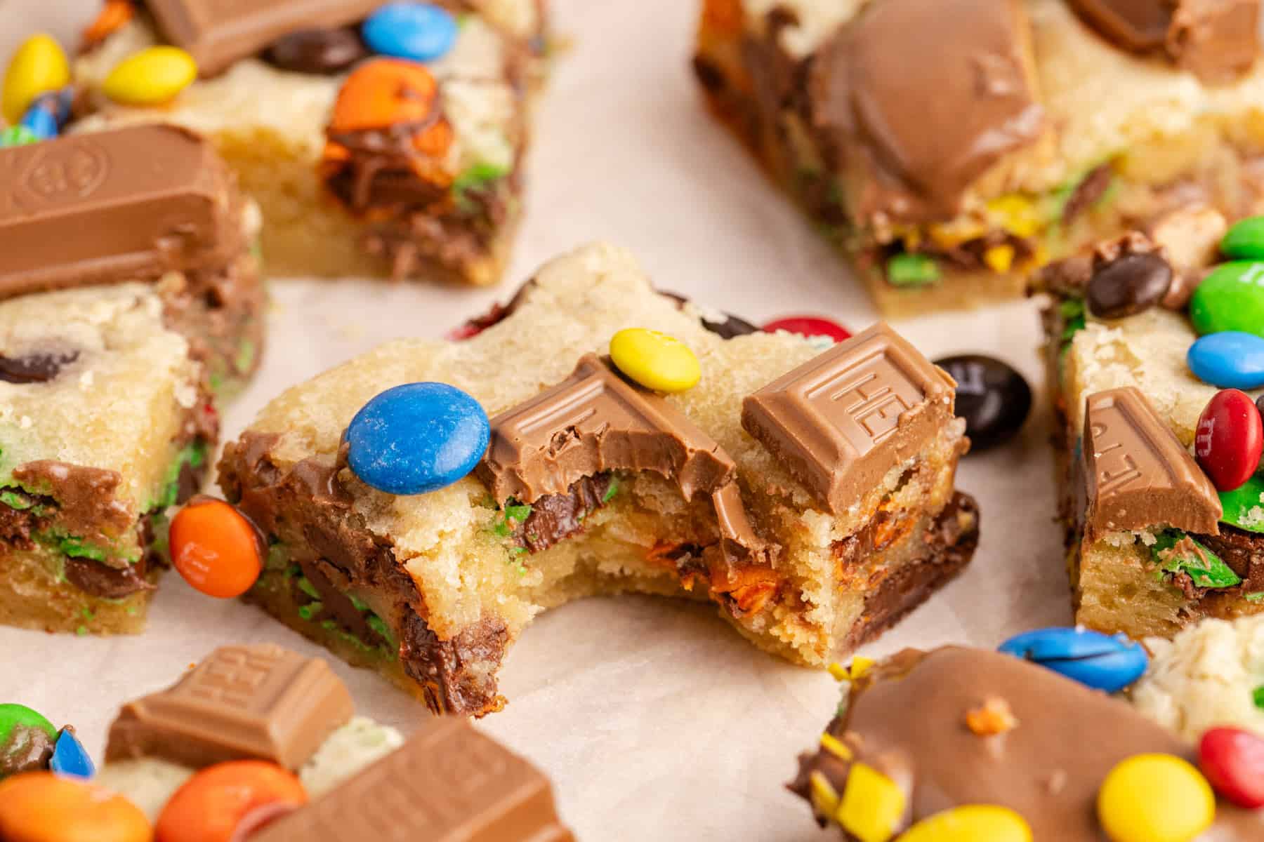 Leftover Candy Cookie Bars on parchment with a bite taken