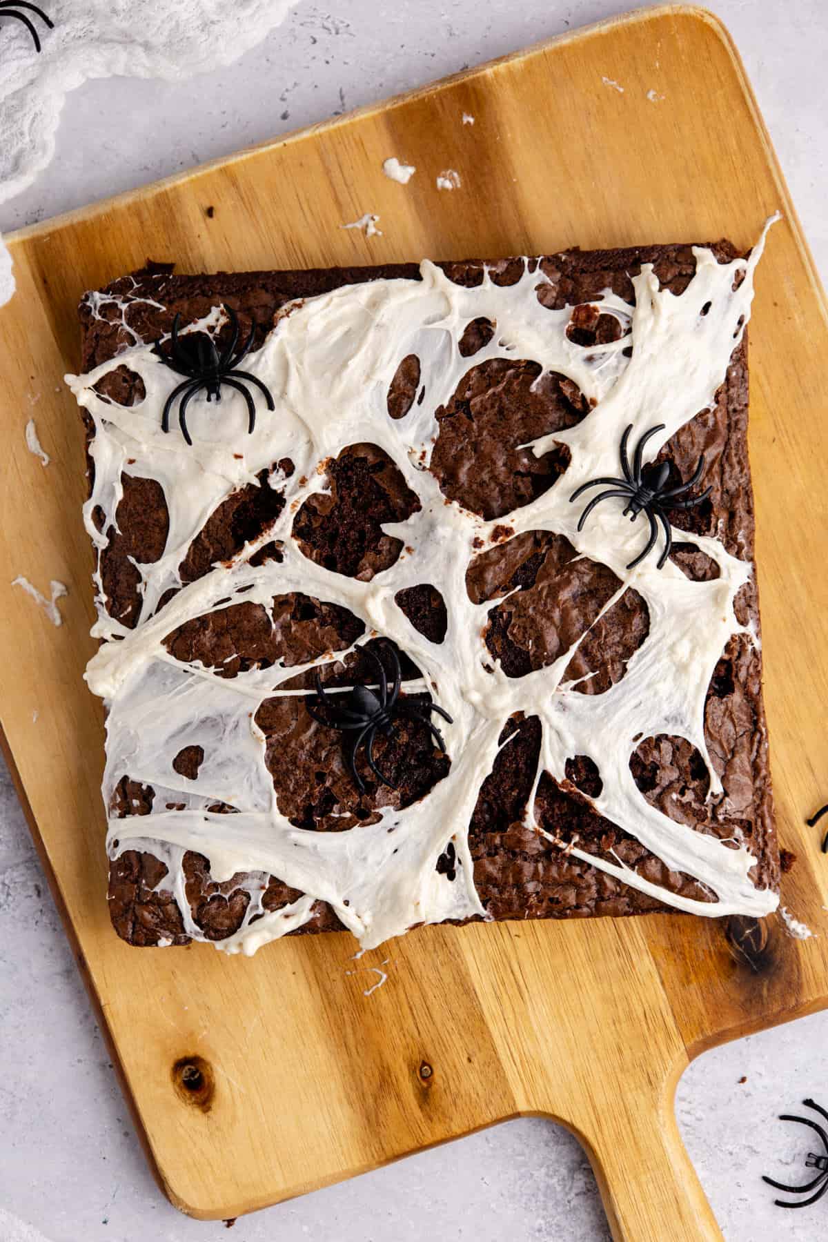 Spiderweb Brownies with plastic spiders on top from above on a cutting board