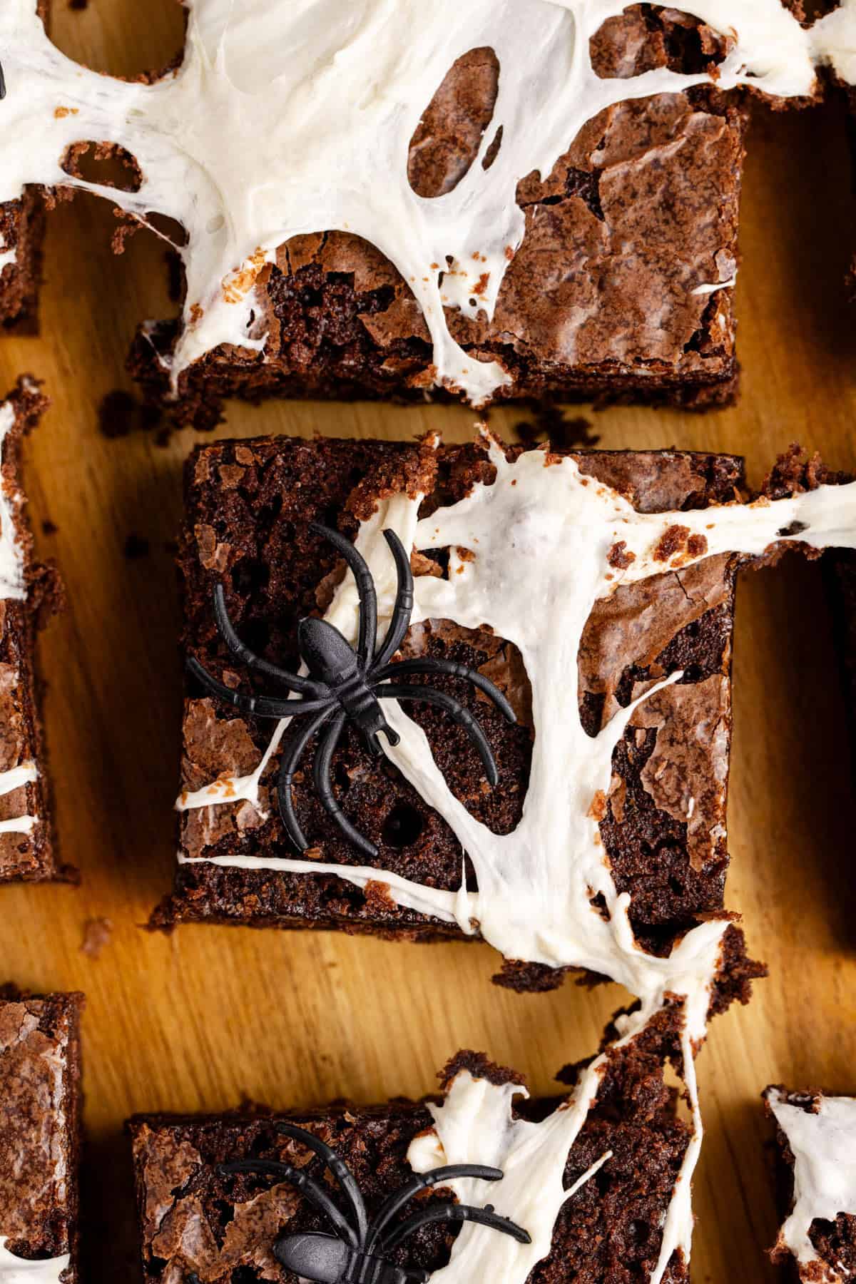 Spiderweb Brownies with plastic spiders on top on a cutting board