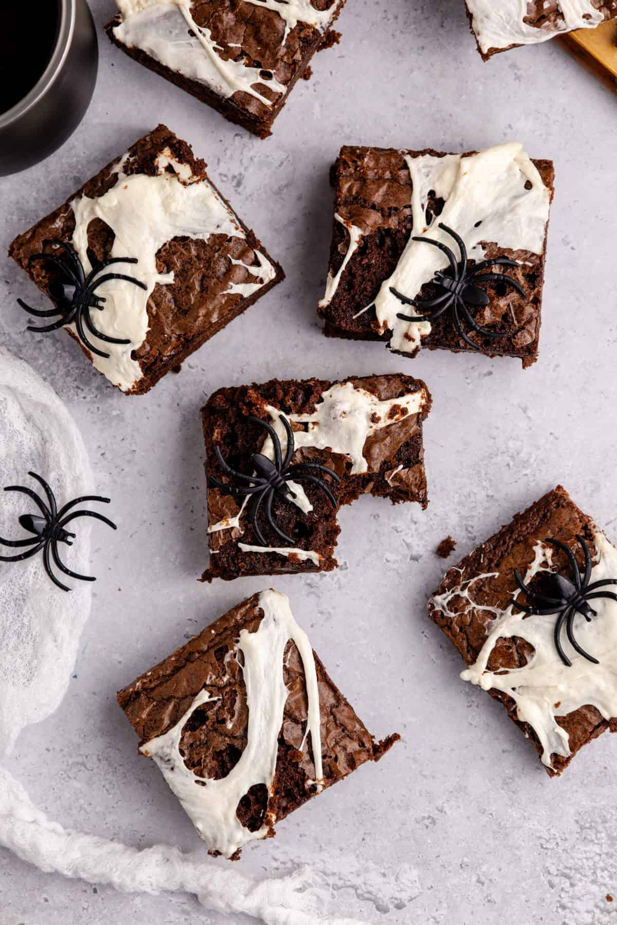 Spiderweb Brownies with plastic spiders on top on a counter from above