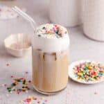 Whimsical Latte with sprinkles on top and a glass stray