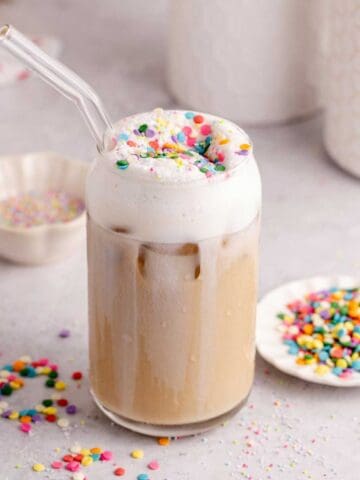 Whimsical Latte with sprinkles on top and a glass stray