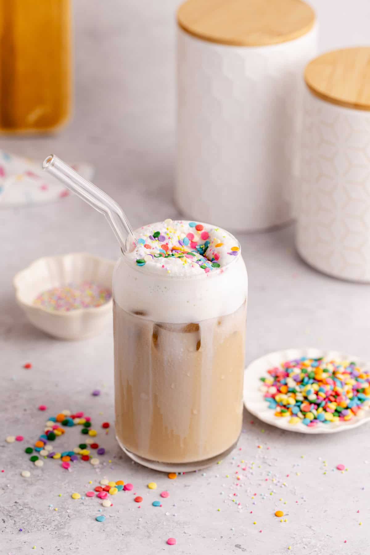Whimsical Latte with sprinkles on top and a glass stray