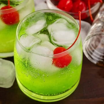 Green Grinch Cocktail Over Ice with Maraschino Cherry