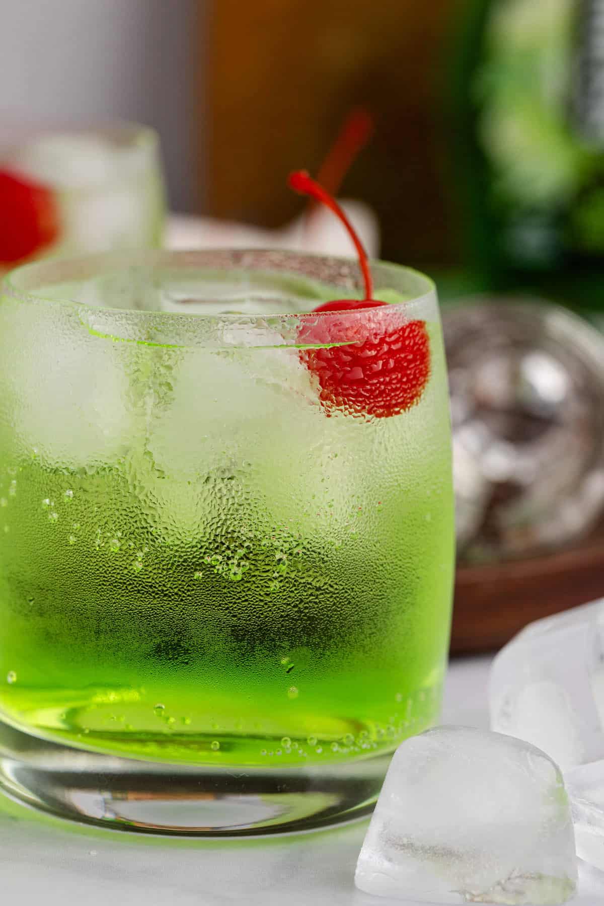 Green Grinch Cocktail Over Ice with Maraschino Cherry