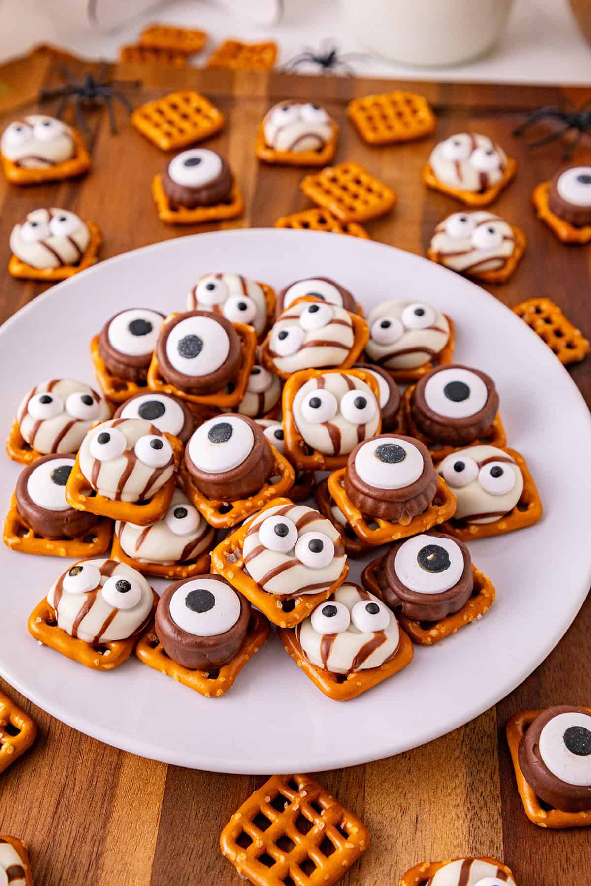 Cute Halloween cookies with eyeball and mummy designs on a white plate.