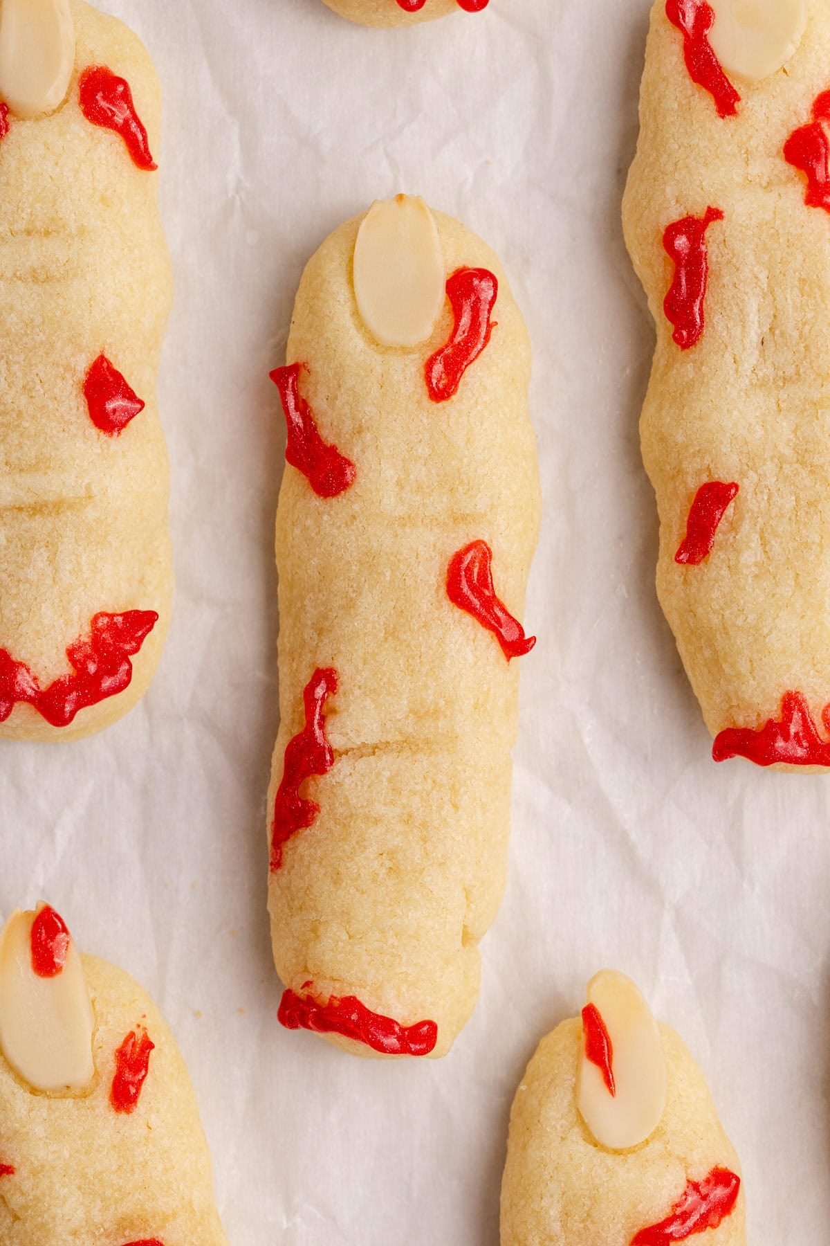 Witch Finger Cookies on parchment paper with icing as blood on them