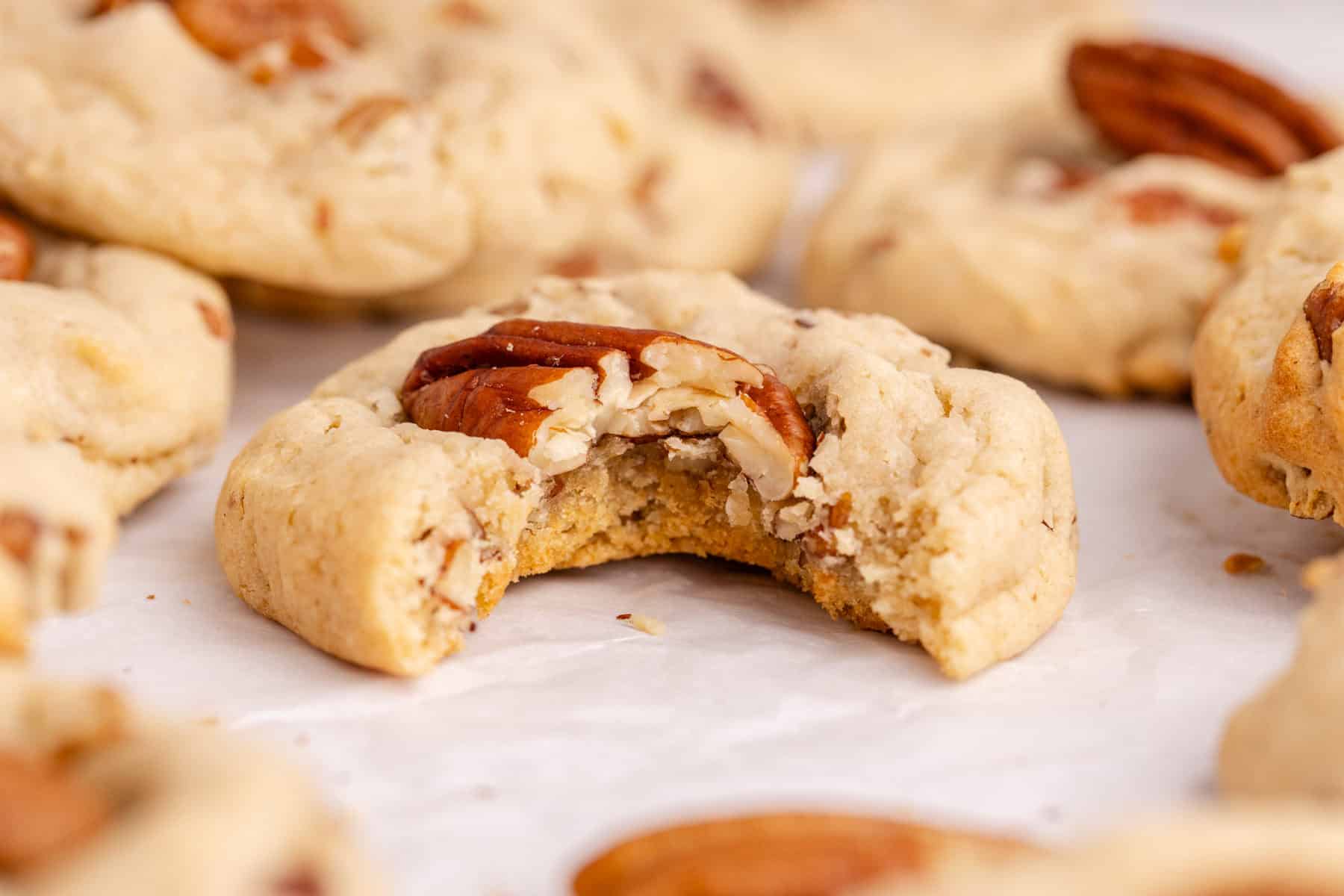Butter Pecan Cake Mix Cookies on a parchment paper up close with a bite taken