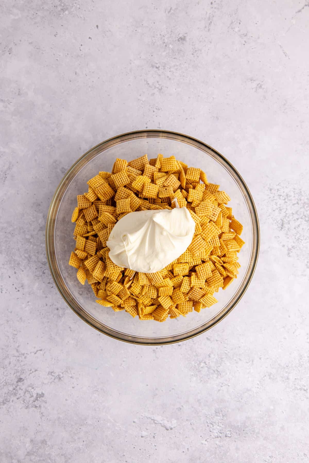 Cake Batter Puppy Chow being made in a large bowl with white chocolate going on