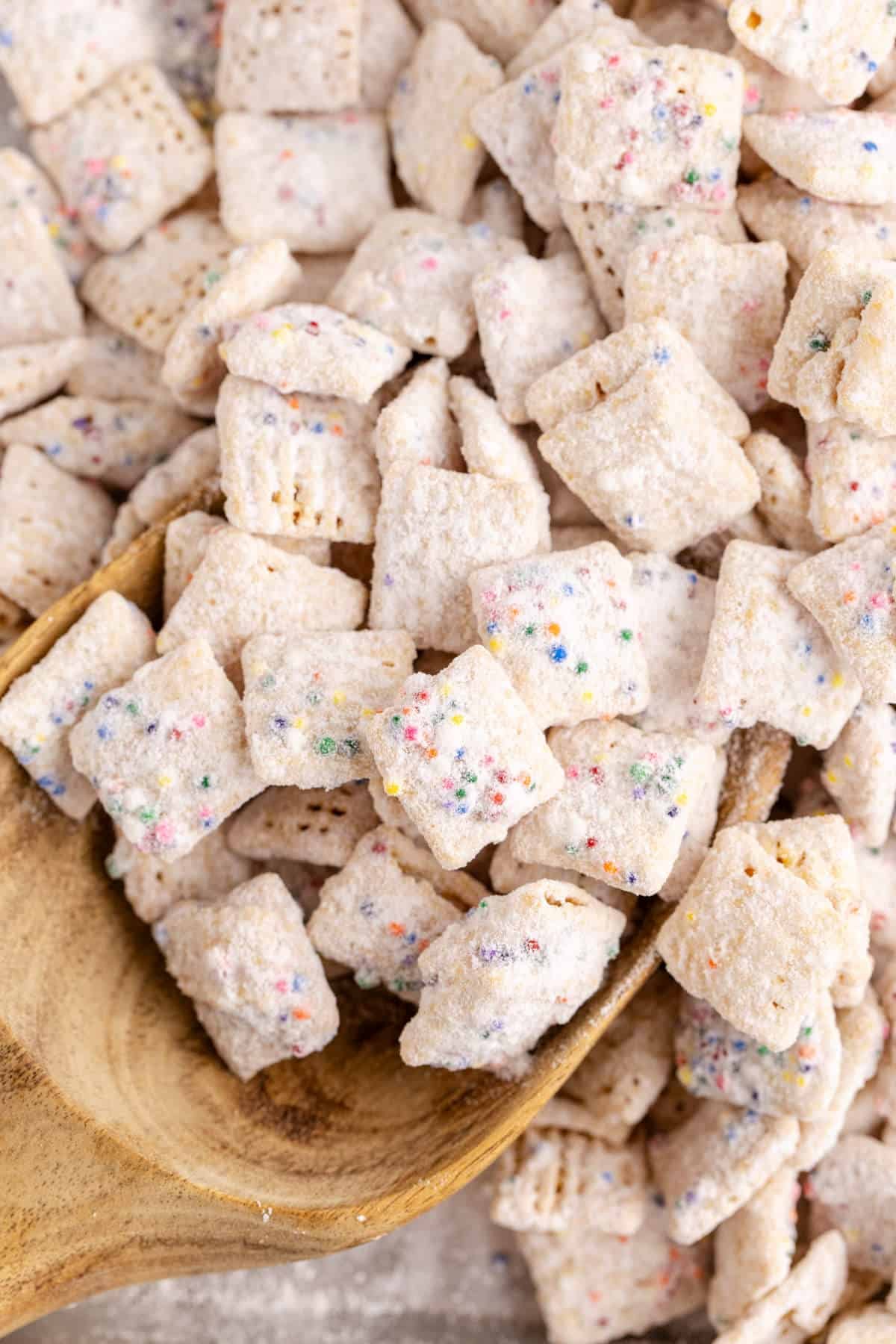 Cake Batter Puppy Chow on a wooden scoop up close