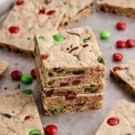 Christmas M&M Cookie Bars stacked with more cookies and M&Ms around