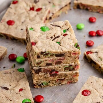 Christmas M&M Cookie Bars stacked with more cookies and M&Ms around