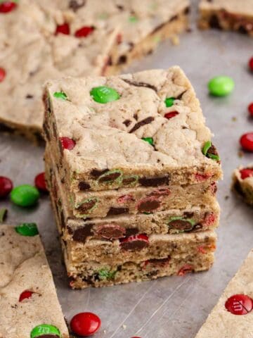 Christmas M&M Cookie Bars stacked with more cookies and M&Ms around