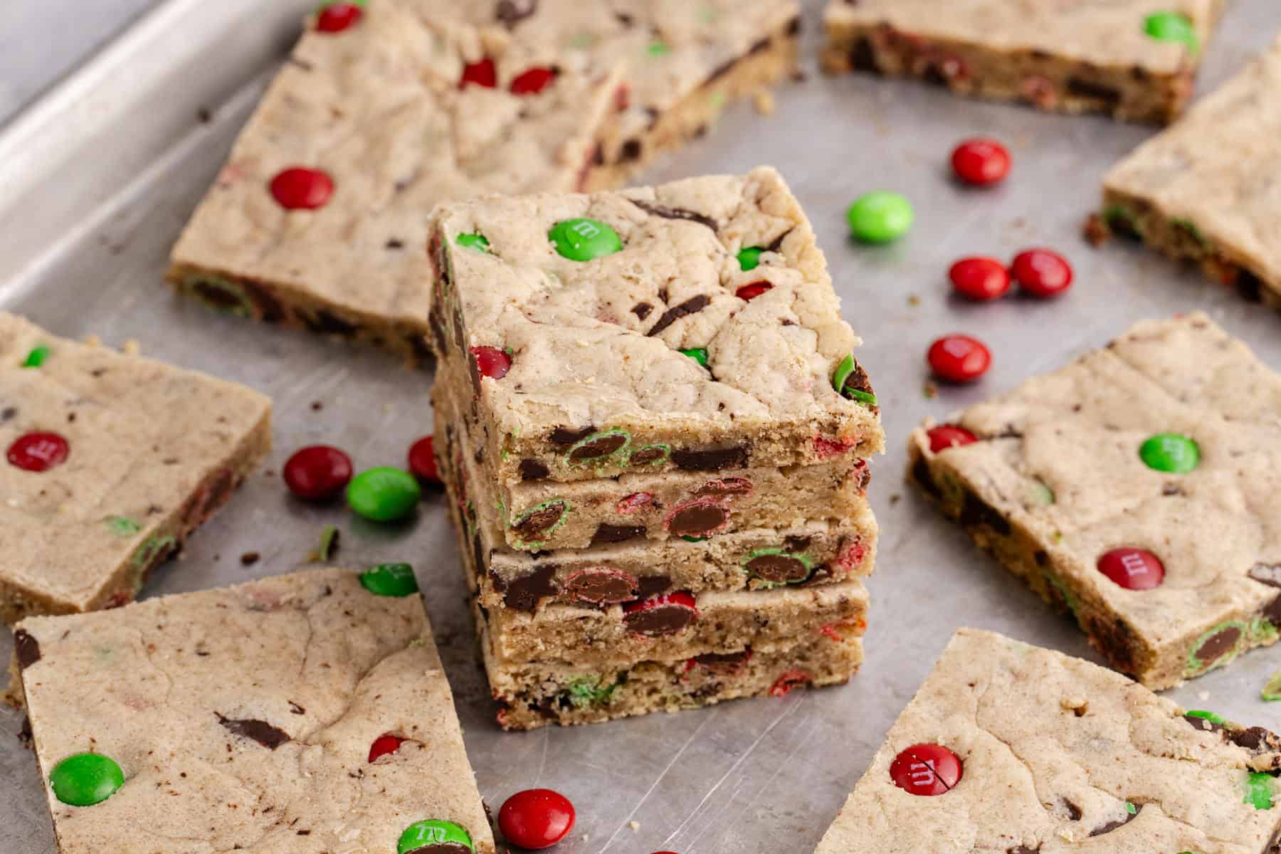 Christmas M&M Cookie Bars stacked with more cookies and M&Ms around
