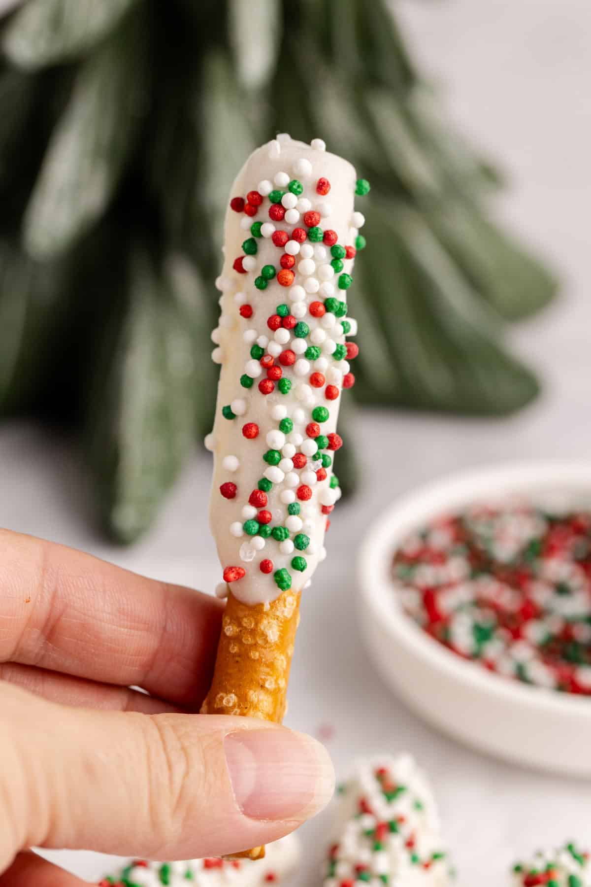 Christmas Pretzel Rods with red, white and green sprinkles being held