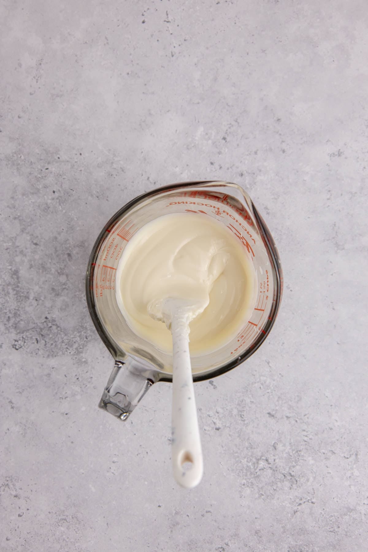 Melted white chocolate in a glass measuring cup