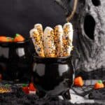 Halloween Pretzel Rods in a cauldron with creepy decor in the back