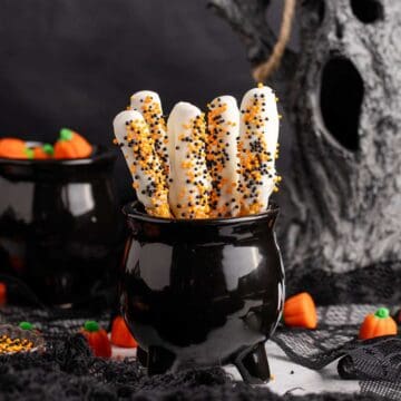 Halloween Pretzel Rods in a cauldron with creepy decor in the back