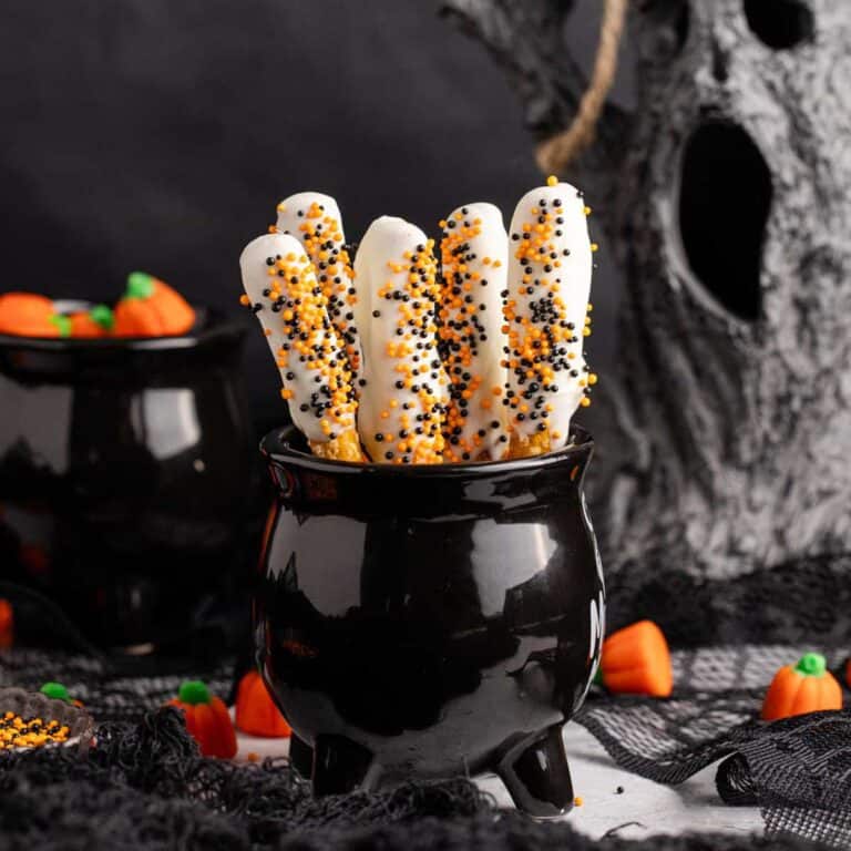 Halloween Pretzel Rods in a cauldron with creepy decor in the back