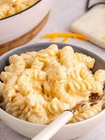 High Protein Mac and Cheese in a bowl with the skillet in the back