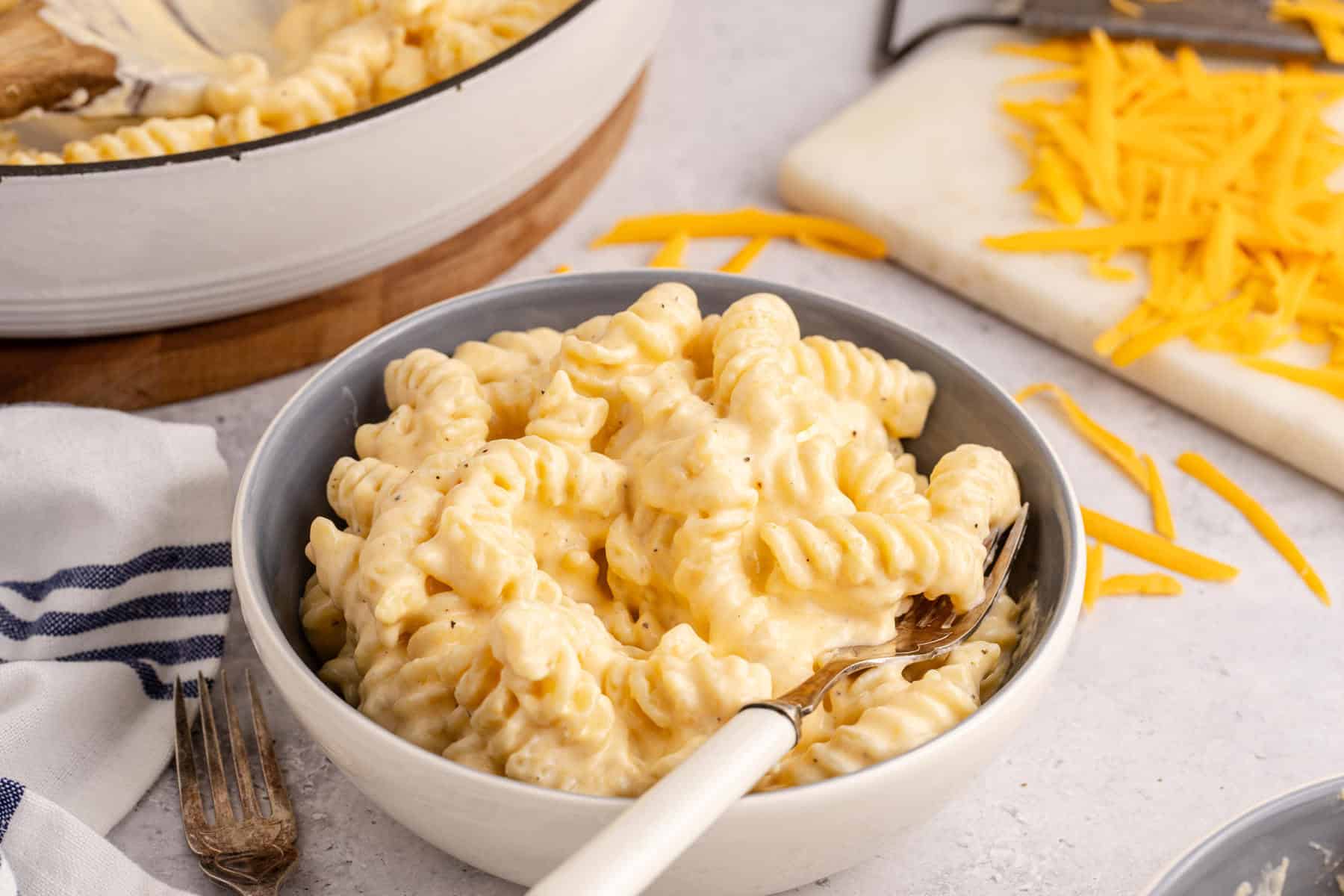 High Protein Mac and Cheese in a bowl with the skillet in the back