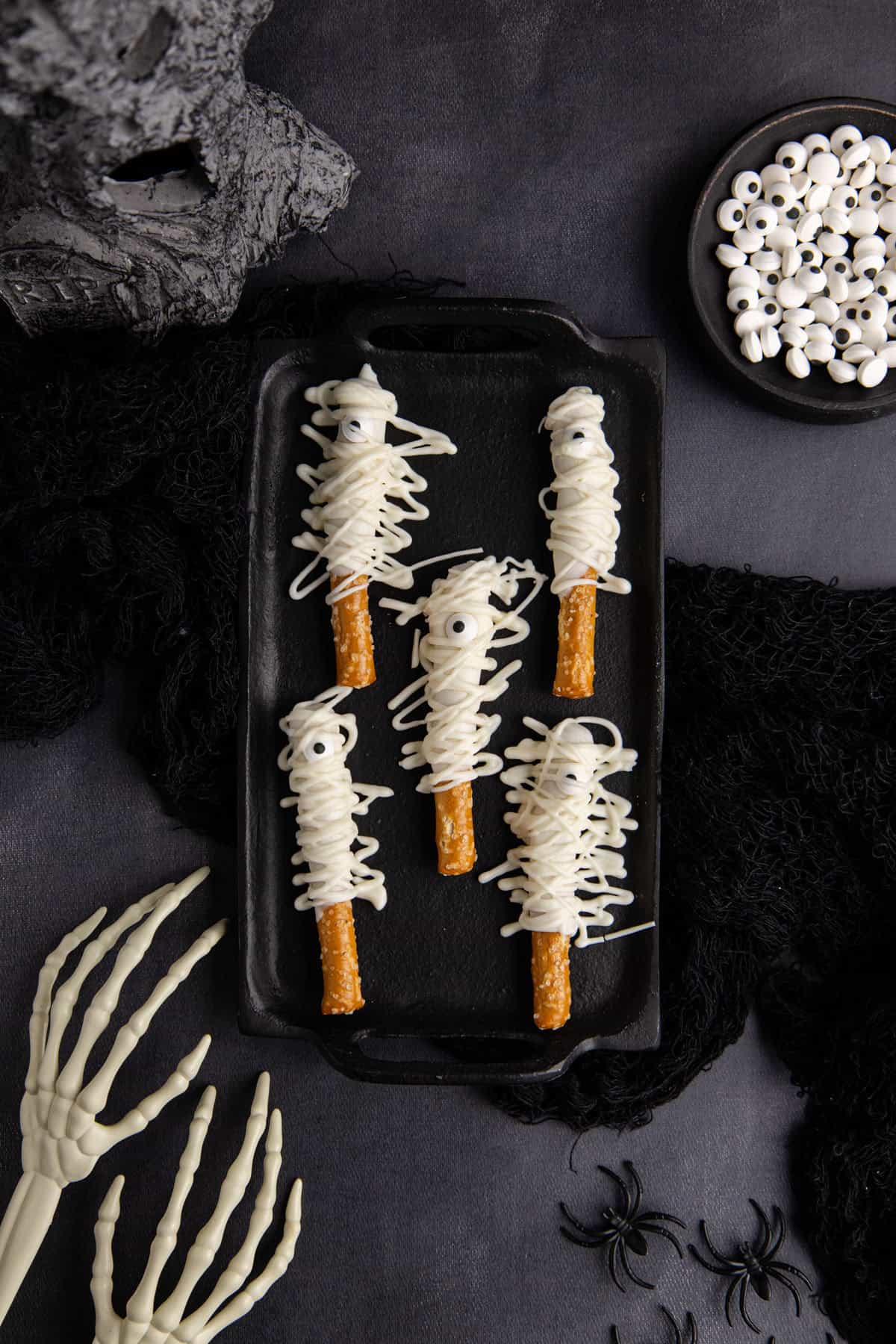 Mummy Pretzel Rods from above on a serving tray with spooky accents around