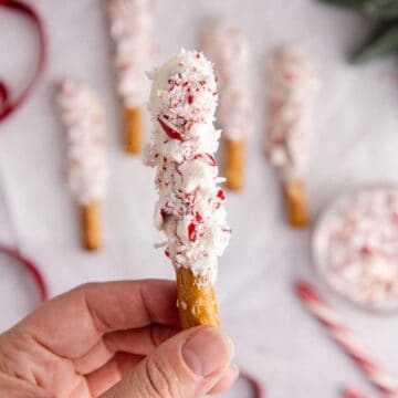 Christmas Pretzel Rods on parchment paper with one being picked up