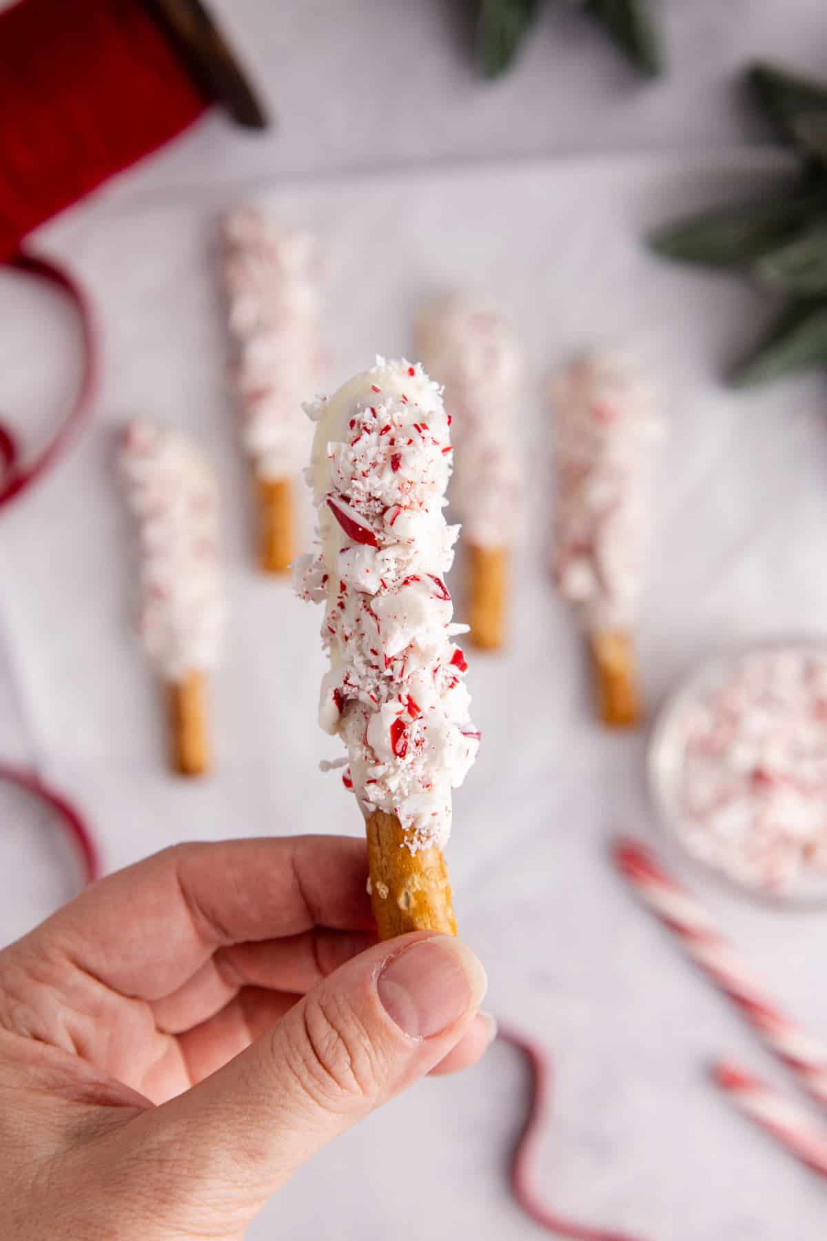 Christmas Pretzel Rods on parchment paper with on being picked up